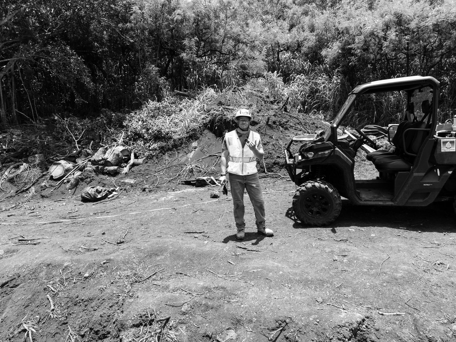 Black and white portrait of a crew member beside a utility vehicle