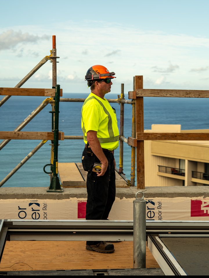 Glazing crew member on a Hawaii high-rise with the ocean behind him