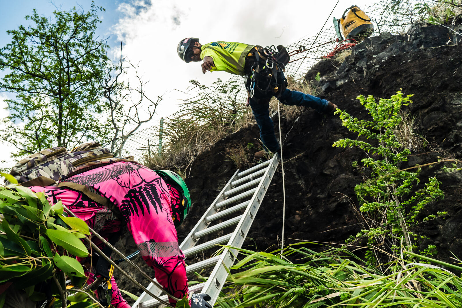 Two crew members using a ladder on the rock face