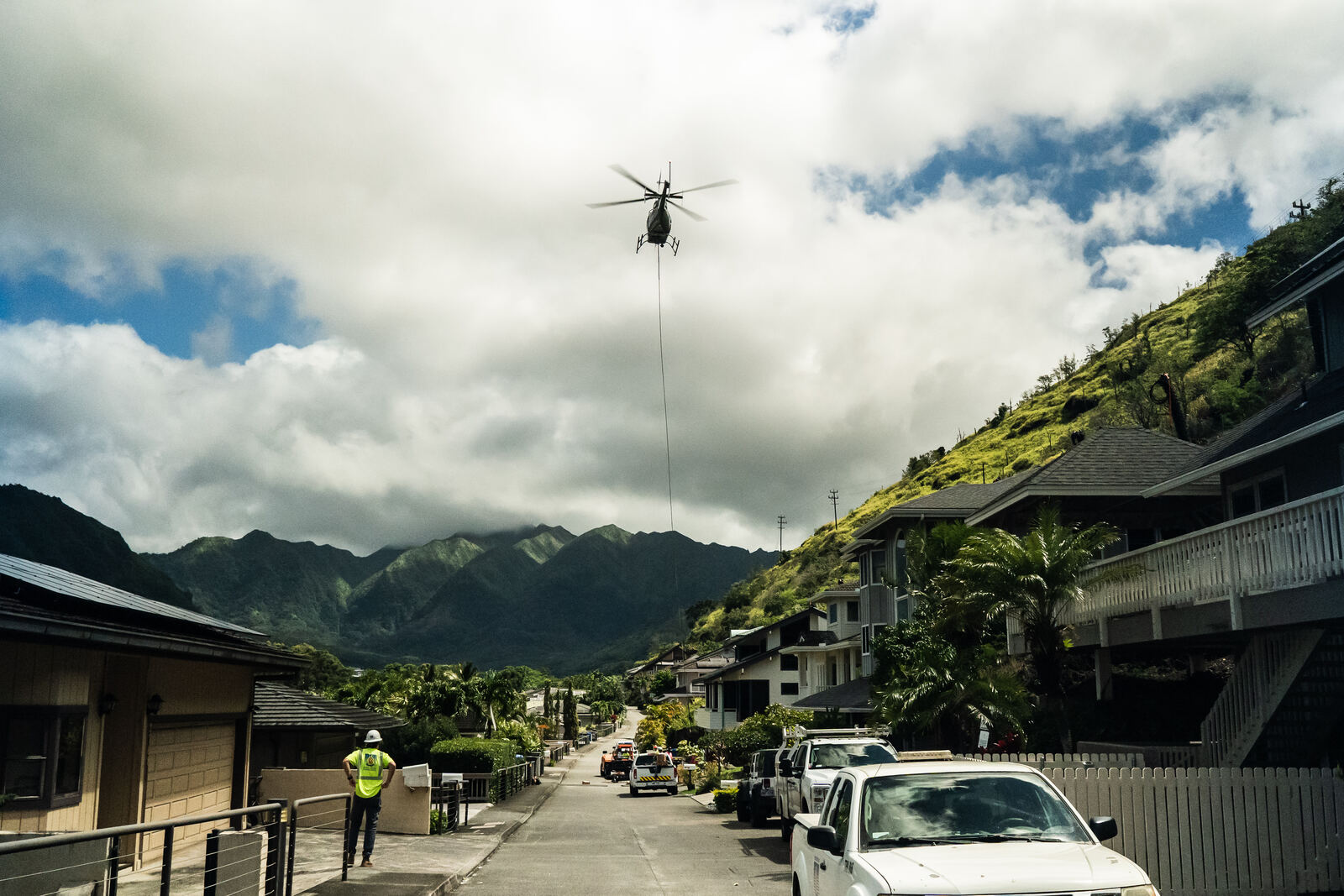 Helicopter carrying a line over a Manoa street